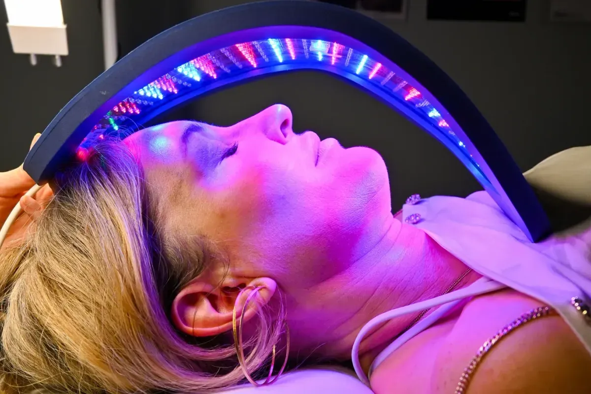 A client resting with her eyes closed under the Celluma red light panel.