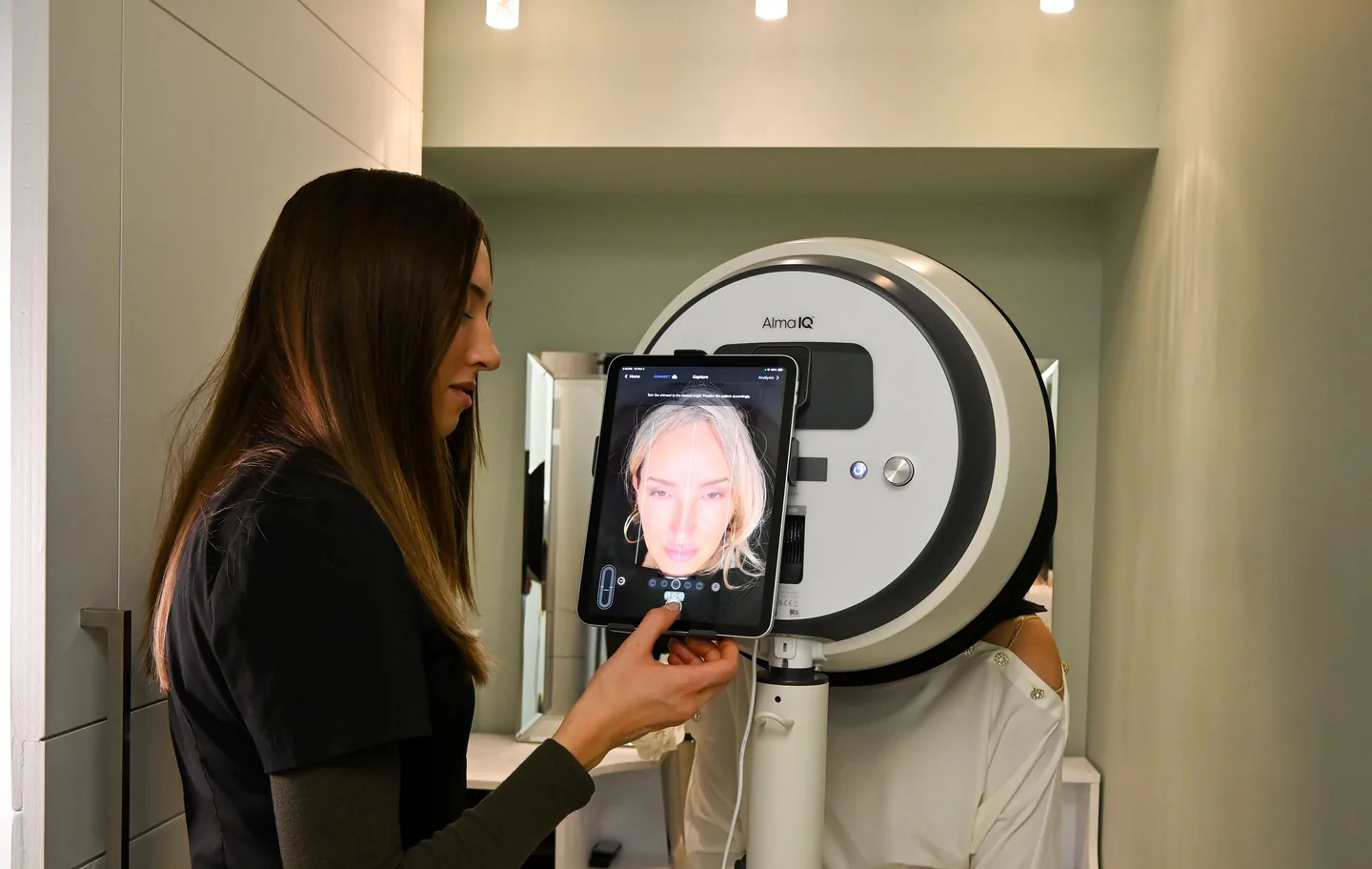 An aesthetician capturing an Alma IQ scan as the client faces the scanner