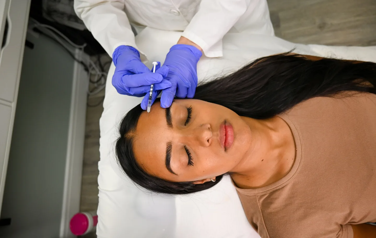 An injector treating a client’s forehead, seen from above