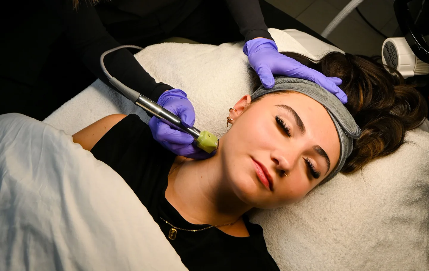 The Fractora handpiece on a client’s neck, the clinician steadying her head